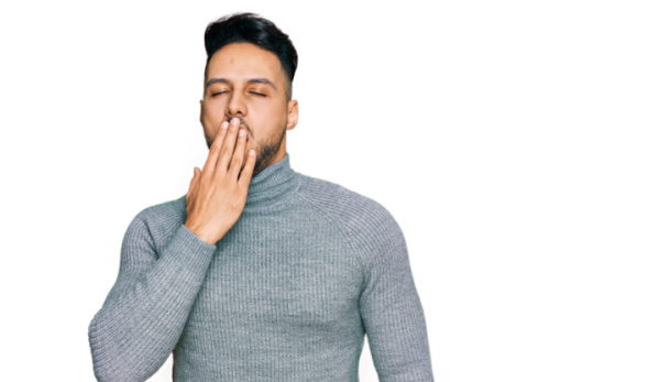 A young man dressed in informal attire, yawning, exhausted, and covering his mouth with his hand. Concept, Why do I yawn when I pray?