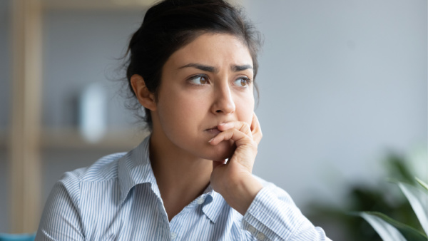 A close-up headshot of a woman thinking about problems or feeling overwhelmed. Scenes include a plant and shelves behind her. Concept, Bible verses for different situations.