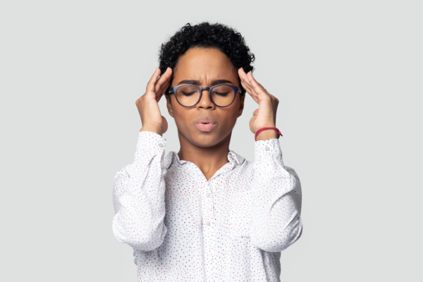 A woman is shown on a gray background concentrating on breathing.