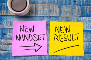 "A new mindset and new results." A motivational and inspirational phrase printed on a wooden background with a cup of coffee.