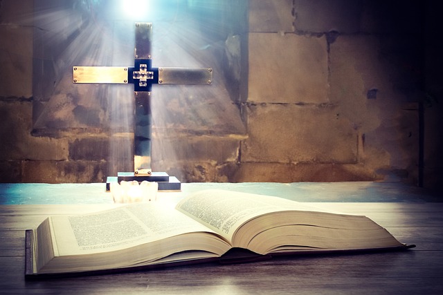 A Gold Cross is displayed in front of an open-faced Bible on a desk in front of a brick background.