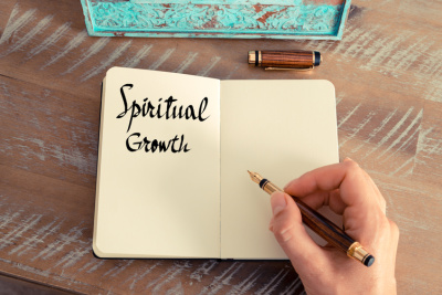 Someone is handwriting "Spiritual Growth" onto a notebook with a fountain pen. The concept pertains to keys for spiritual growth.