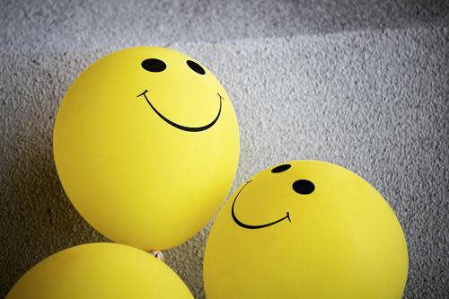 A set of three smiling balloons on a plain gray background.